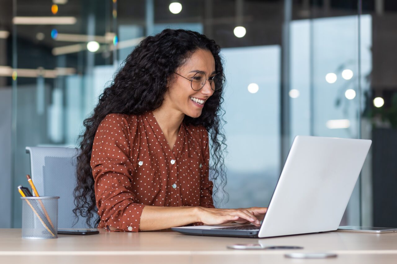 Young,And,Happy,Hispanic,Woman,Working,In,Modern,Office,Using