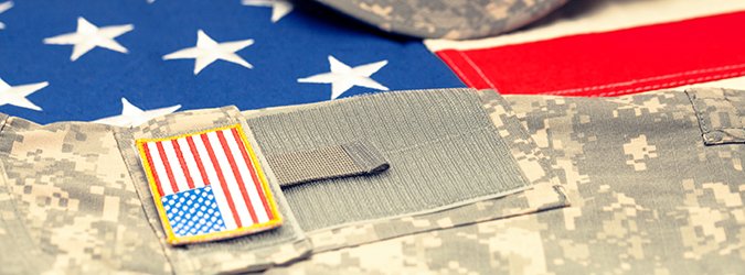 USA flag with US military uniform over it – studio shot. Filtered image: cross processed vintage effect.