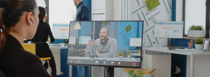 Picture of a woman sitting at her desk interviewing a man on her computer.