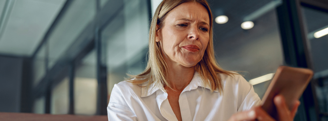 Women wearing a white dress shirt holding a cell phone.