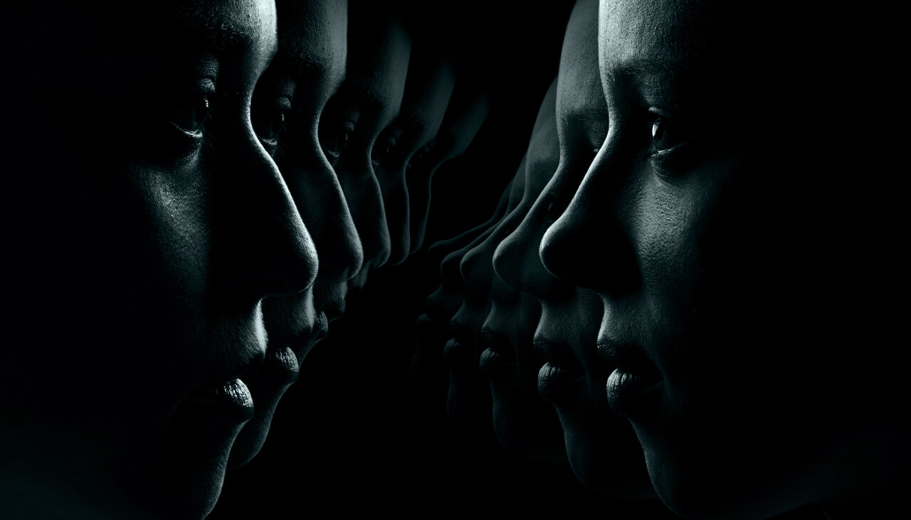 A dark, artistic image showing repeated side profiles of a persons face, gradually fading into the shadows, creating a sense of reflection or echo.