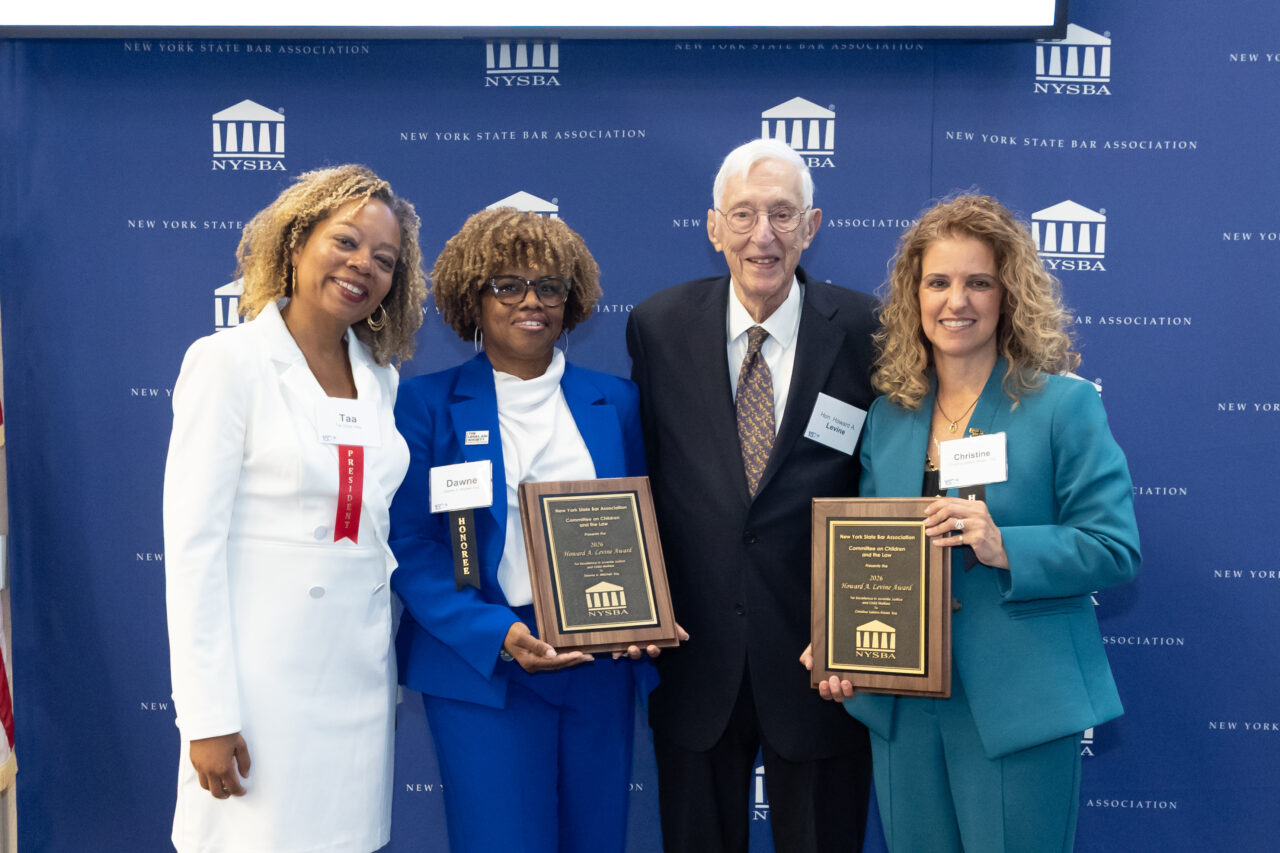 Four people pose together at an award event, three holding plaques. They stand before a New York State Bar Association backdrop, smiling for the camera.