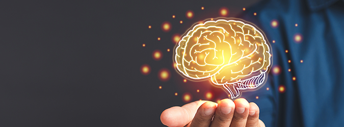 A person holds out their hand with a glowing, illustrated brain hovering above the palm, surrounded by small orange light particles against a dark background.