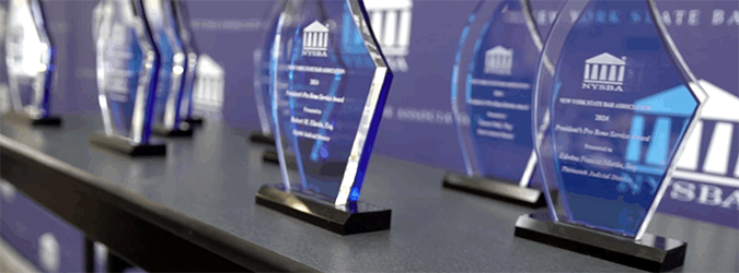 A row of clear glass awards shaped like shields, each bearing the New York State Bar Association logo and text.