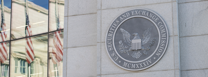 Seal of the U.S. Securities and Exchange Commission on a stone building wall, with reflections of American flags in the adjacent windows.