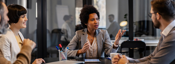 A diverse group of professionals sitting around a table in a modern office, engaged in a discussion.