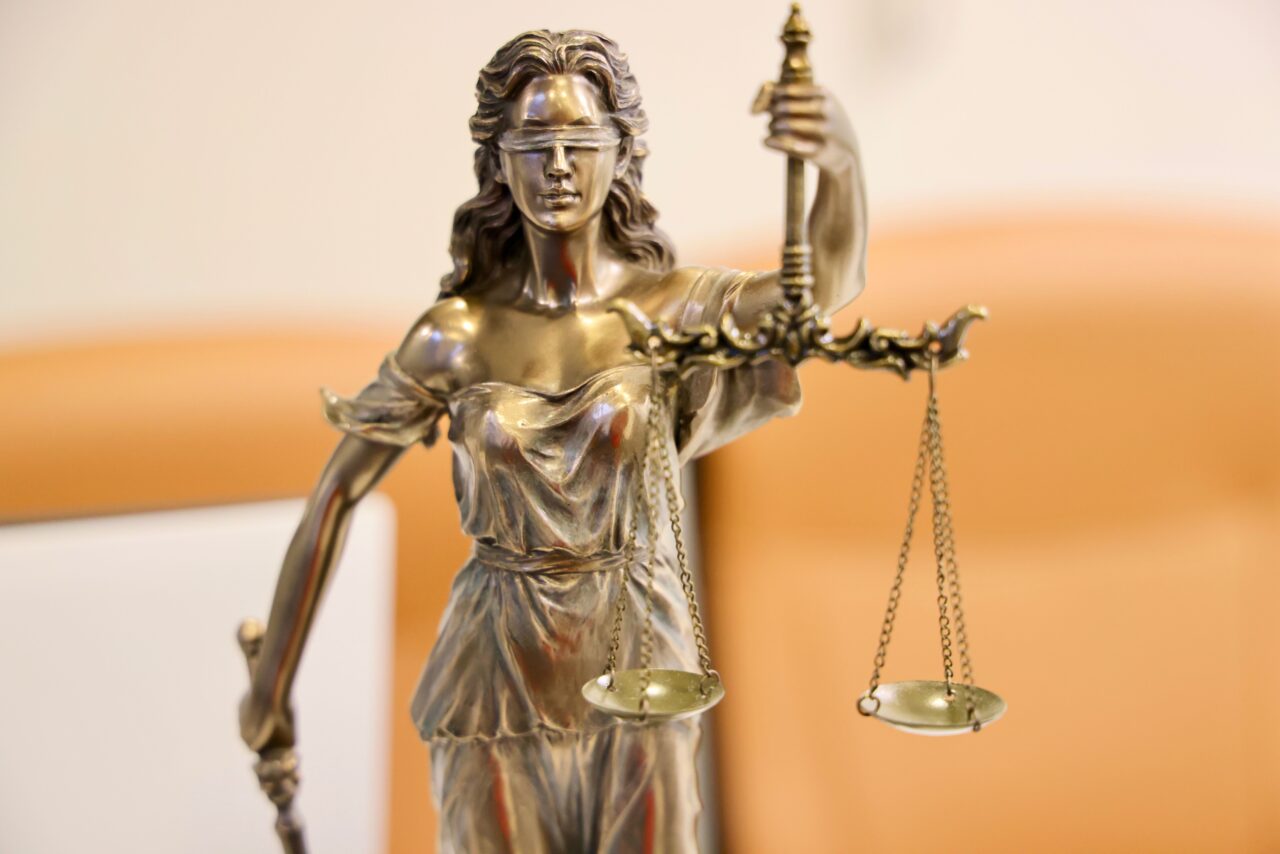 A bronze statue of Lady Justice holding a sword and balanced scales.